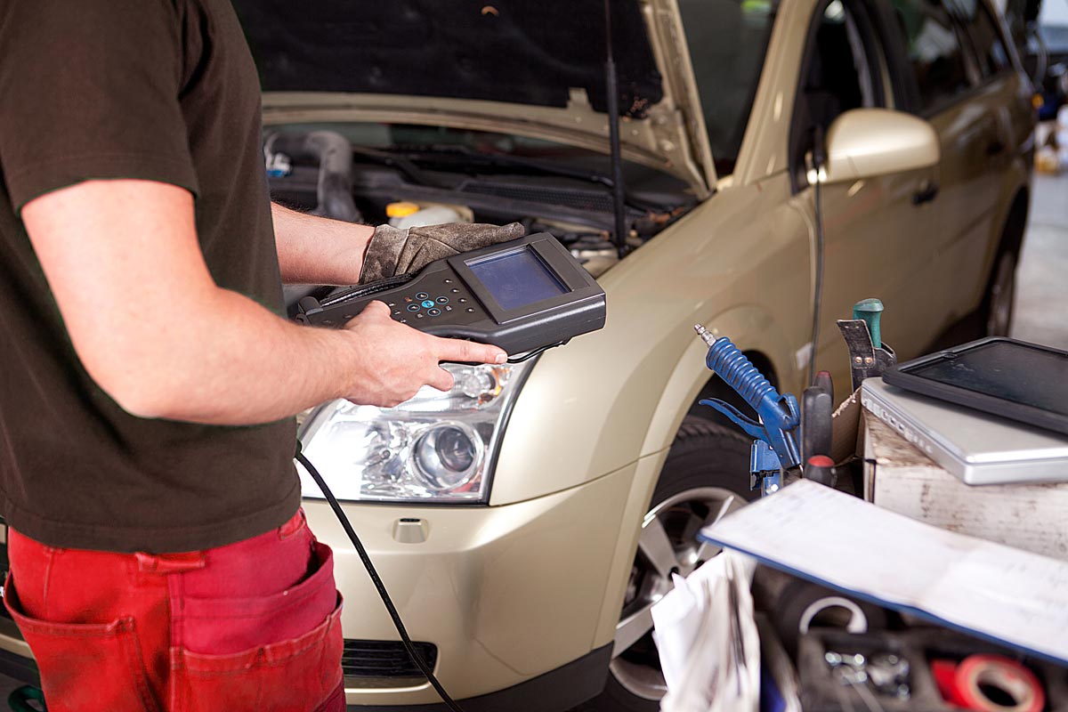Mechanic with car engine diagnostic equipment